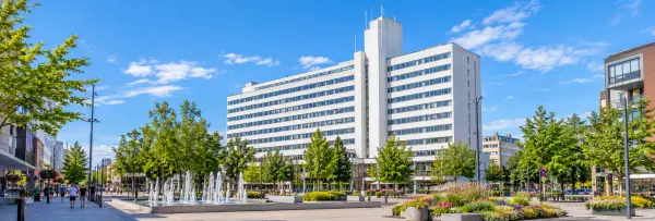 Kouvola city centre with a modern white building, fountain, trees and landscaped plaza in Finland