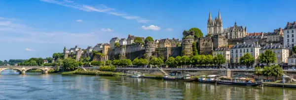 Angers, France, with Château d'Angers, the Maine River and historic city skyline under a blue sky.