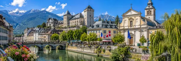 Chambéry, France, with a historic castle, riverside old town, and snow-capped Alpine mountains