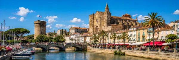 Fréjus, France, with a historic cathedral, medieval tower, palm-lined waterfront, and boats