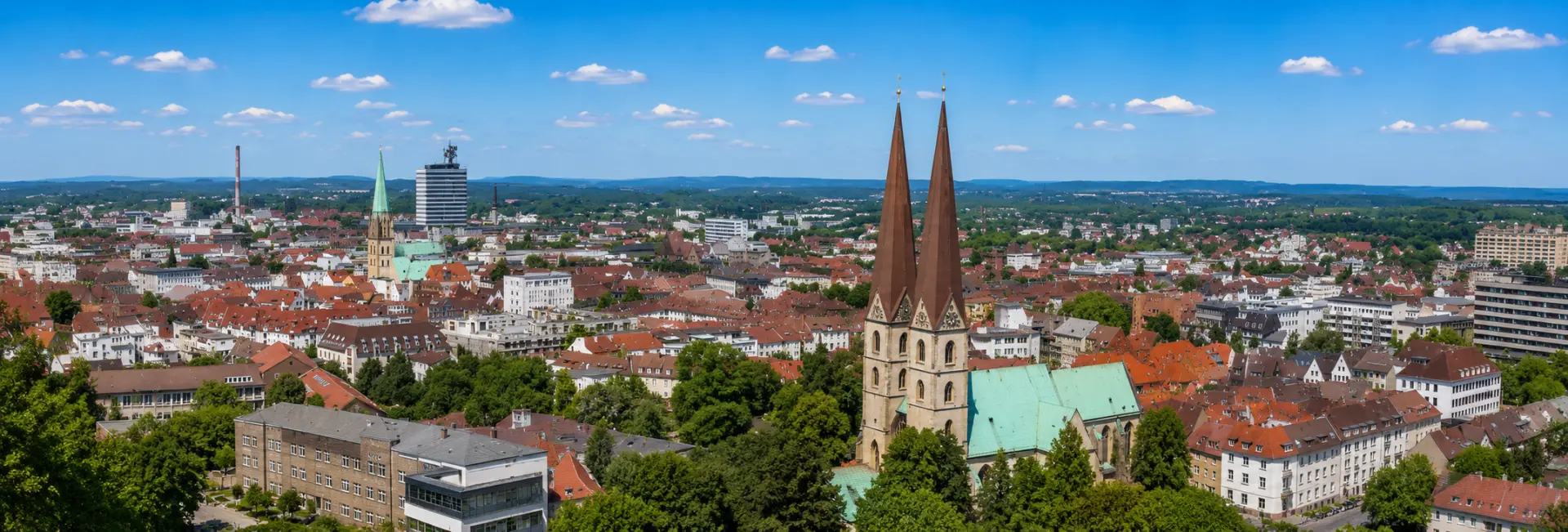 Bielefeld, Germany skyline with historic churches, Sparrenburg Castle tower, modern buildings, and green surroundings