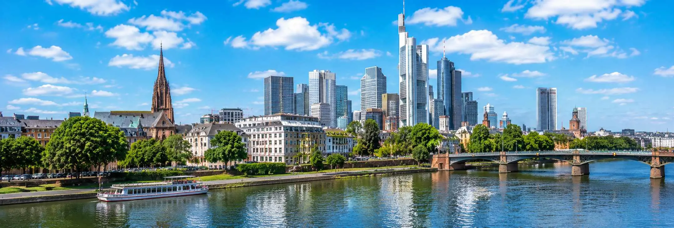 Panoramic view of Frankfurt featuring the Main River, modern skyline, and historic city landmarks under a clear blue sky