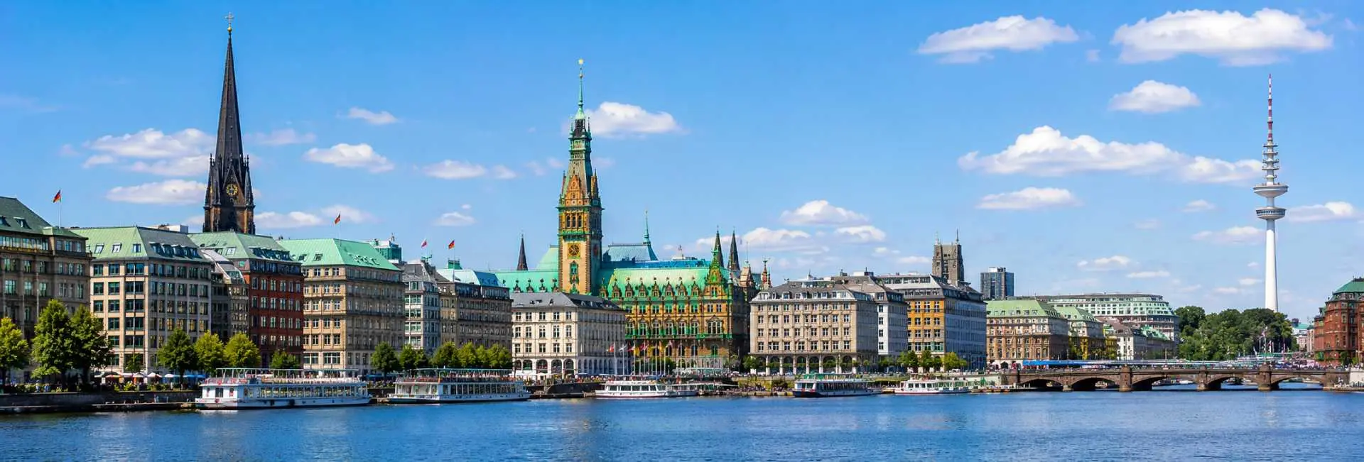 Hamburg Germany waterfront with historic Rathaus, boats, church spires and city skyline