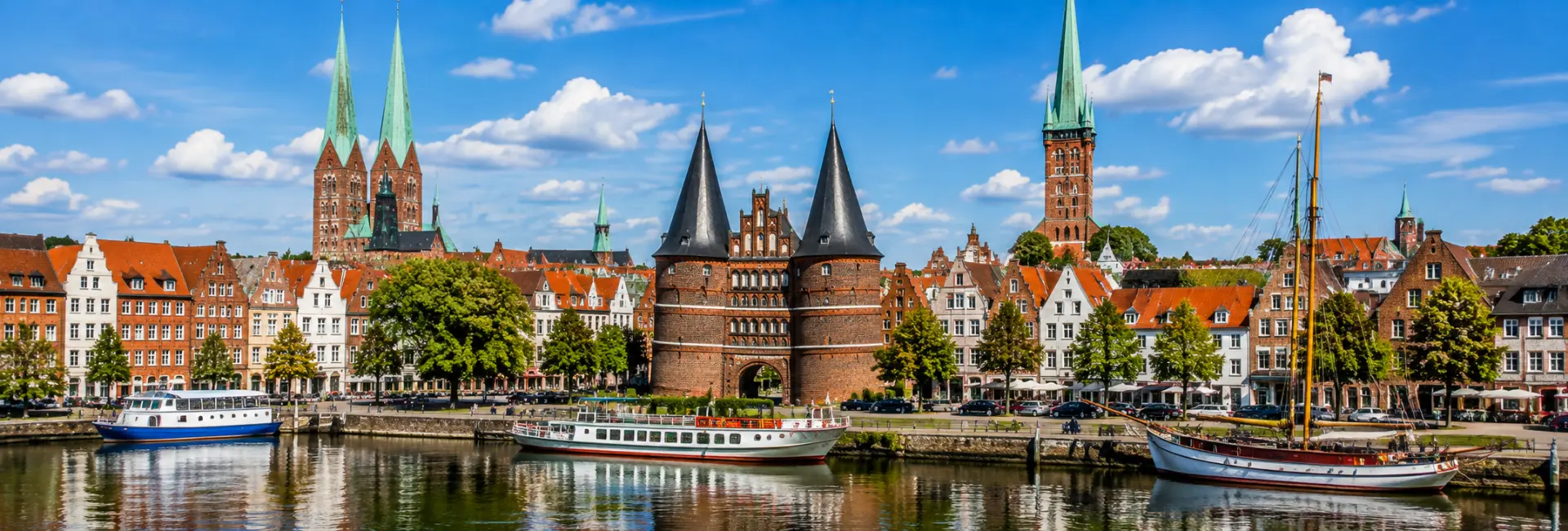 Lübeck, Germany skyline with Holstentor, historic buildings, church spires and riverfront