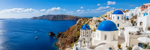 Santorini landscape with whitewashed buildings, blue domes and the Aegean Sea