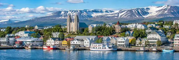 Akureyri, Iceland waterfront with colorful houses, Akureyri Church, boats, and snow-capped mountains