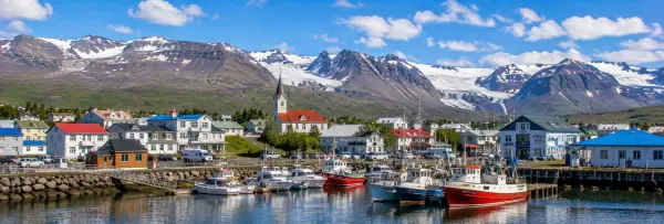 Höfn, Iceland harbor with fishing boats, colorful houses, church, and snow-capped mountains