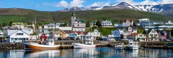Húsavík, Iceland harbor with colorful houses, fishing boats, church, and snow-capped mountains