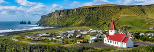 Vík, Iceland village with a red-roofed church, black-sand beach, cliffs, and sea stacks