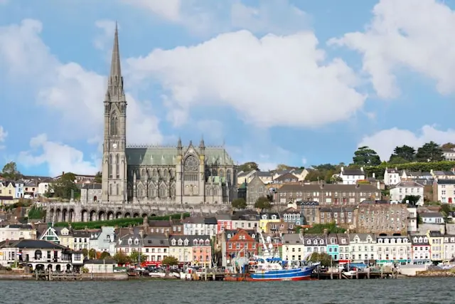 St. Fin Barre’s Cathedral overlooking Cork’s waterfront with colorful buildings and boats