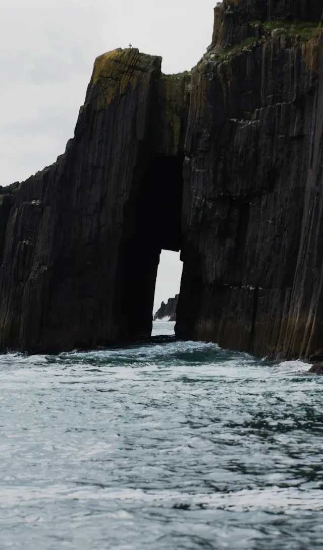 Dramatic sea cliffs and a natural rock arch along the rugged Dingle Peninsula coastline