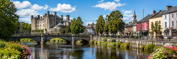 Kilkenny Castle overlooking the River Nore with historic buildings and a stone bridge in Kilkenny, Ireland.