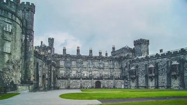 Kilkenny Castle courtyard with medieval stone towers, battlements, and surrounding green lawn