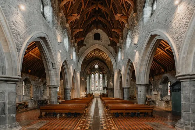 Interior of a historic stone church in Kilkenny with Gothic arches, wooden vaulted ceiling, and stained glass
