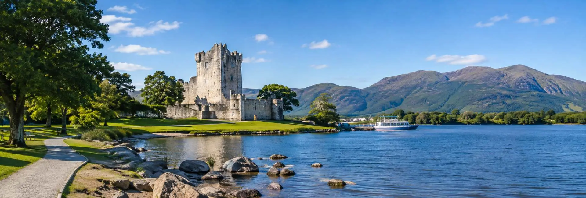 Ross Castle beside Lough Leane in Killarney, Ireland, with mountains and a scenic lakeside landscape.
