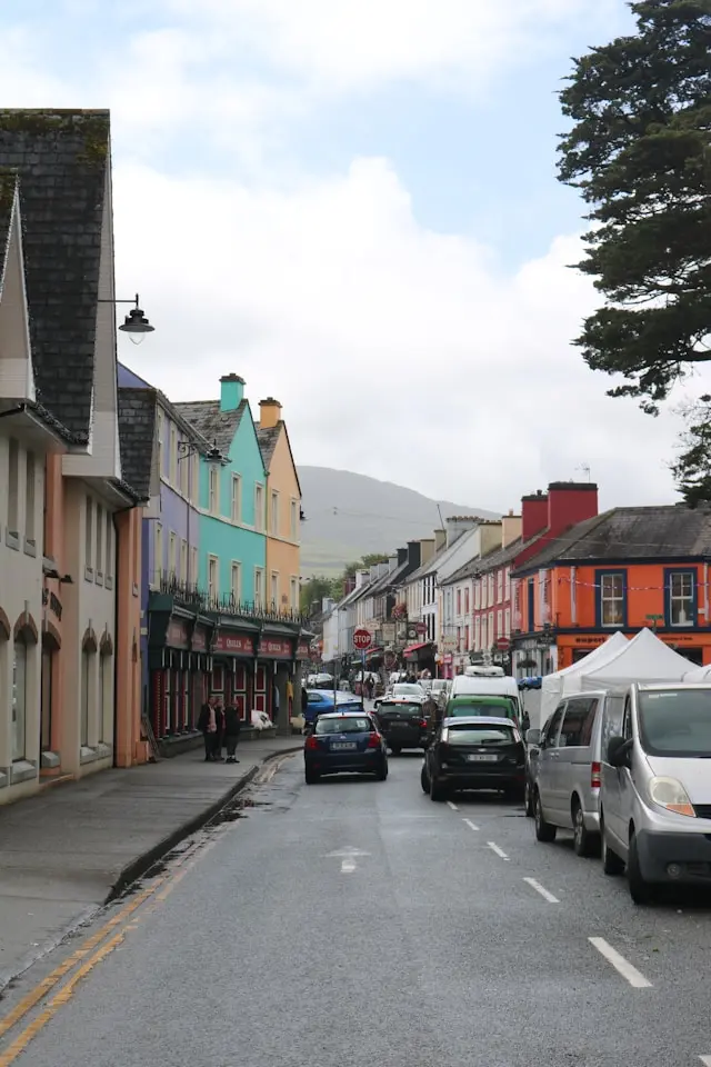 Colorful street in Killarney lined with traditional shops and buildings beneath a mountain backdrop