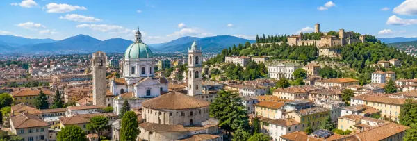 Aerial panoramic view of Brescia, Italy, with historic rooftops, churches, castle and surrounding mountains