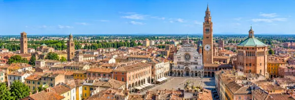 Panoramic view of Cremona, Italy, with the Duomo, Torrazzo, Baptistery and historic terracotta rooftops.