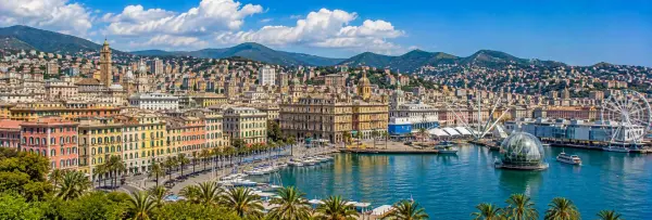 Genoa, Italy waterfront with historic buildings, marina, palm trees and surrounding hills
