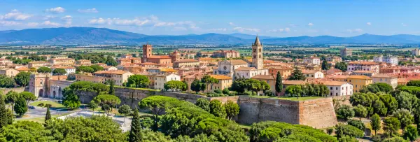 Panoramic view of Grosseto, Italy, with historic city walls, Tuscan rooftops, cathedral and distant mountains.