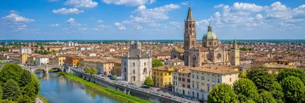 Panoramic view of Parma, Italy, with historic buildings, Parma Cathedral, terracotta rooftops, and the river
