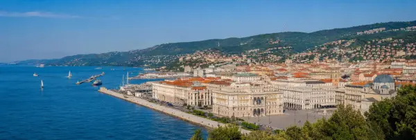 Panoramic view of Trieste, Italy, with the Adriatic Sea, historic waterfront, terracotta rooftops, and green hills