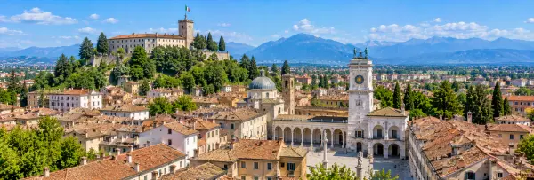 Panoramic view of Udine, Italy, with Udine Castle, Piazza Libertà, historic rooftops and the Alps.