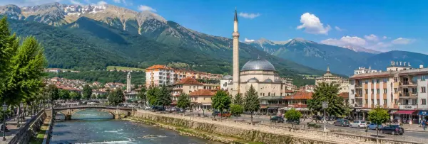 Panoramic view of Peja, Kosovo, with the Lumbardhi River, mosque and dramatic Rugova Mountains