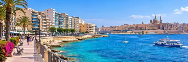 Sliema waterfront promenade with turquoise sea and Valletta skyline across the harbor in Malta