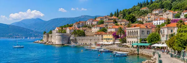 Herceg Novi waterfront with Forte Mare fortress, blue Adriatic waters and mountains across the Bay of Kotor.