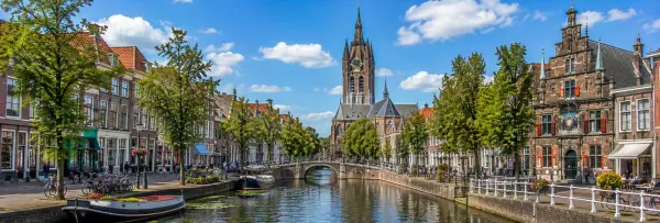 Delft Netherlands canals with historic brick houses, bridges and Nieuwe Kerk
