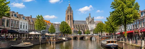 Den Bosch, Netherlands, with a scenic canal, historic buildings, boats, and the Gothic St. John’s Cathedral.