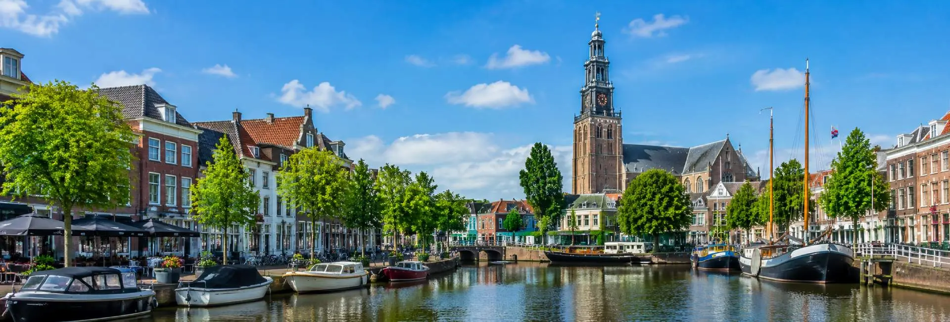 Leeuwarden, Netherlands historic canal with boats, traditional buildings, and the Oldehove tower