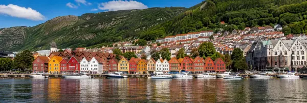 Bergen Norway waterfront with colorful Bryggen buildings, harbor boats and green mountains