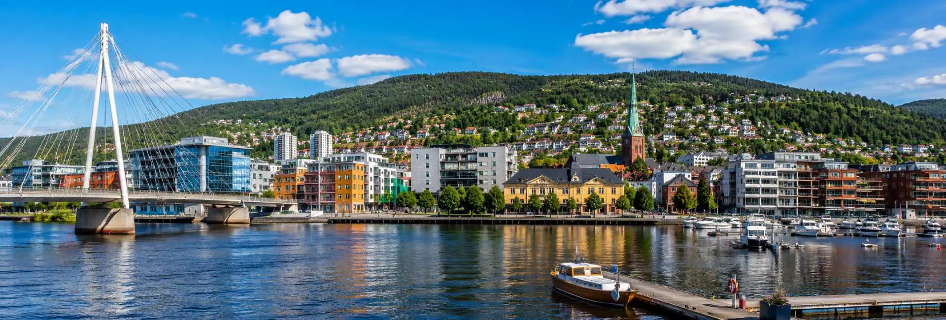 Drammen, Norway waterfront with Ypsilon Bridge, marina, historic buildings and forested hills