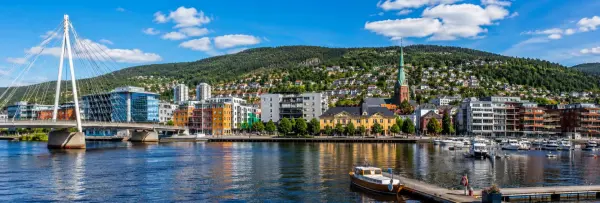 Drammen, Norway waterfront with Ypsilon Bridge, marina, historic buildings and forested hills