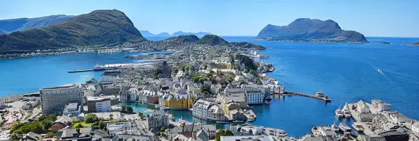 Ålesund, Norway panoramic view of colorful waterfront buildings, harbor, and surrounding mountains