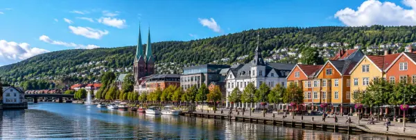 Skien, Norway waterfront with colorful historic buildings, boats, church and forested hills