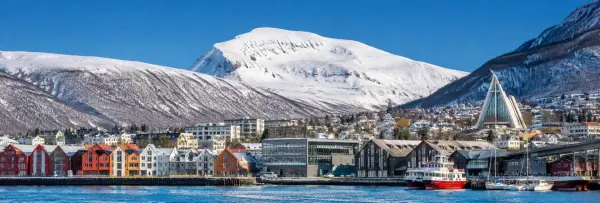 Tromsø, Norway waterfront with colorful buildings, Arctic Cathedral and snow-covered mountains