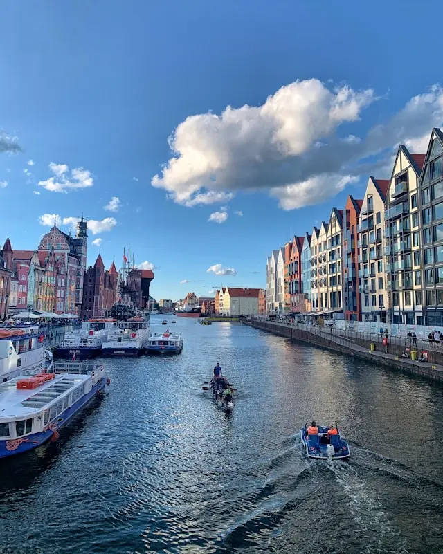 Gdańsk waterfront with historic colorful buildings and boats along the Motława River