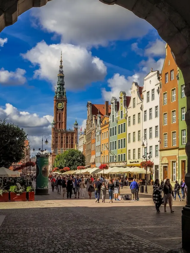 Long Market street in Gdańsk with colorful historic buildings, outdoor cafes, and St. Mary's Church tower