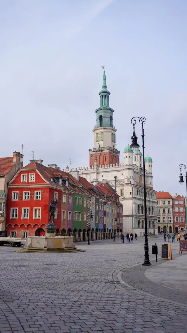Colorful historic buildings and a town hall tower surrounding a cobblestone city square