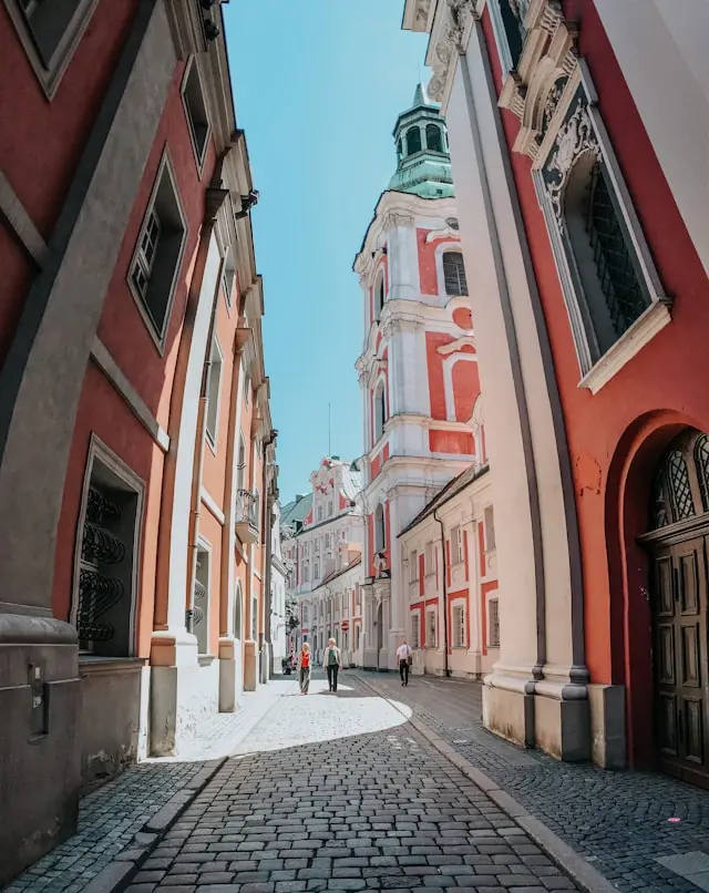 Historic European street with colorful buildings, cobblestone pavement, and a prominent church tower