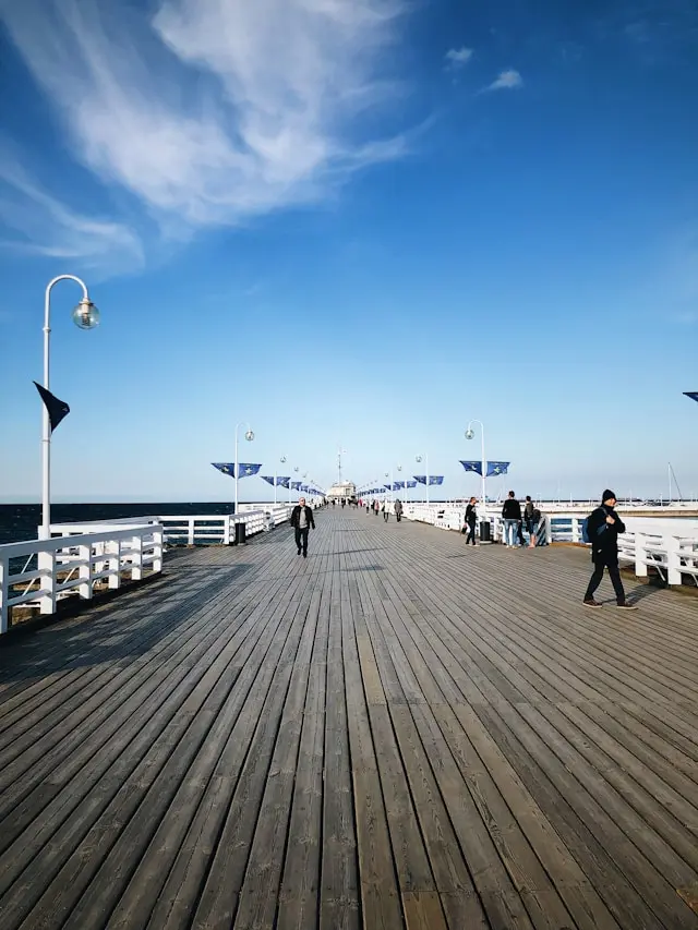 Wooden seaside pier extending into the Baltic Sea with people walking along it