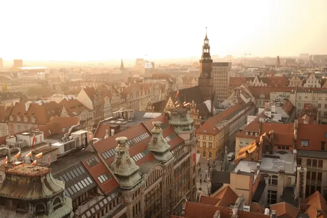 Aerial view of a historic European city center with red-roofed buildings and a central clock tower
