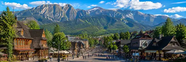 Krupówki Street in Zakopane with traditional wooden buildings and the dramatic Tatra Mountains in Poland.