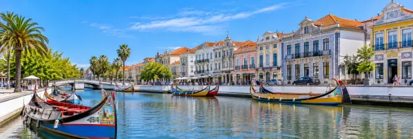 Aveiro, Portugal, with colorful moliceiro boats, canals, palm trees, and historic Art Nouveau buildings.