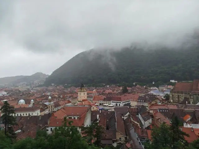 Panoramic view of Brașov Old Town beneath misty mountains in Romania