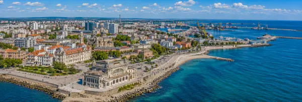 Aerial panoramic view of Constanța, Romania, with the Black Sea, historic casino, harbor, and city skyline