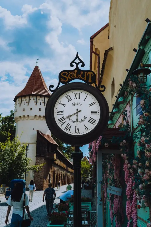 Historic clock and medieval tower on a cobblestone street in Sibiu, Romania